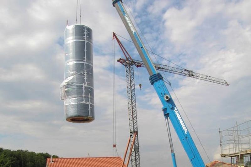 Speicher wird mit Kran auf die Baustelle geliefert, 10'000 Liter Wassertank für Sonnenheizung